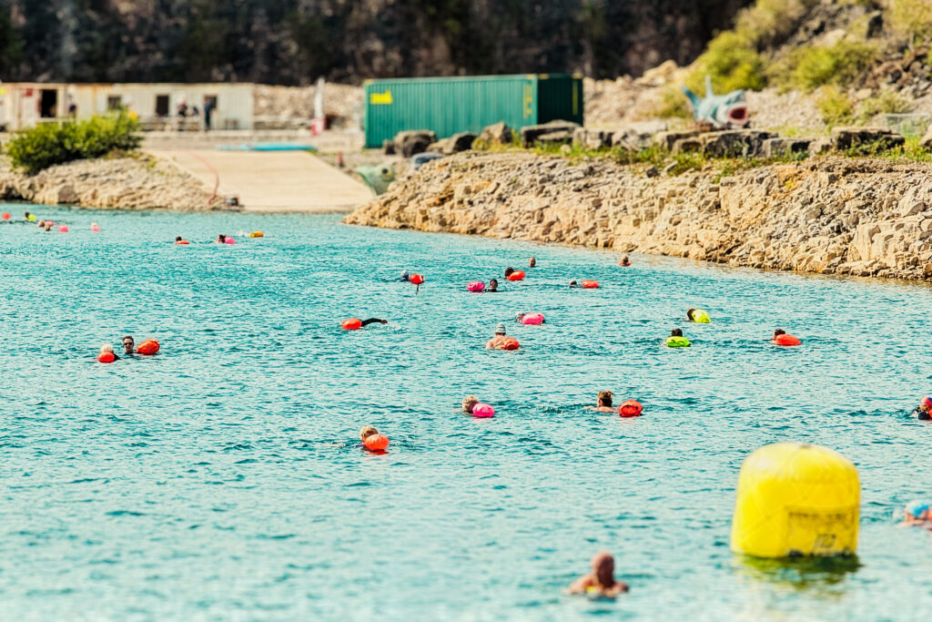 A group of open water swimmers with colourful tow floats enjoying the swim routes in The Lake at Cromhall Quarry.